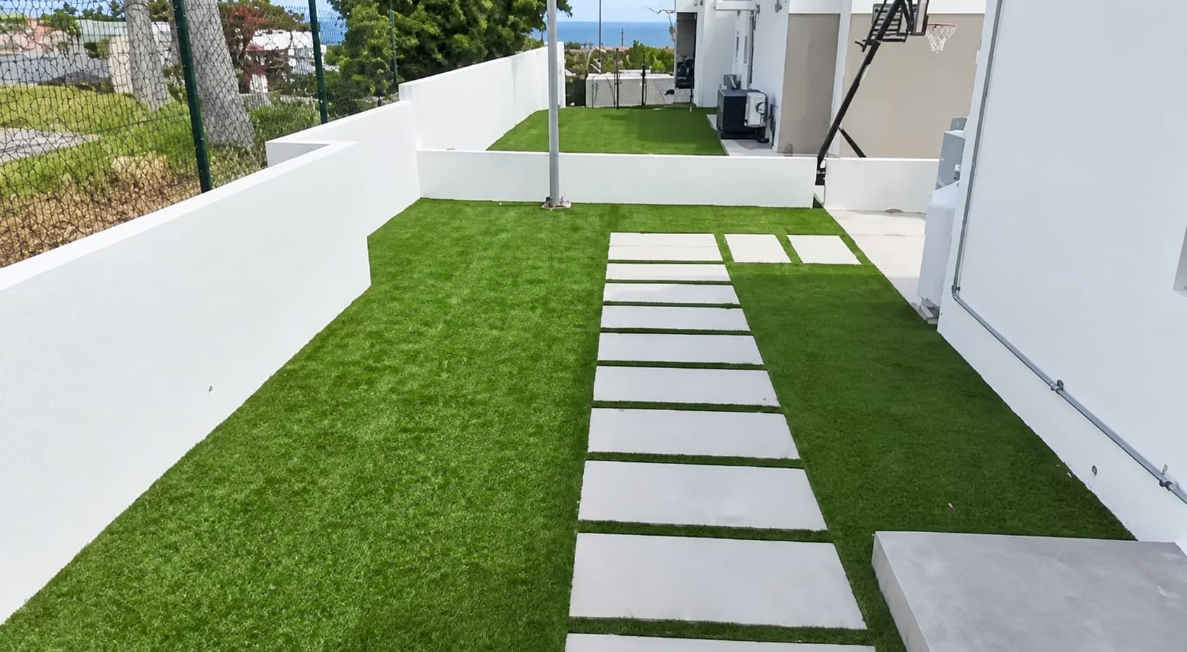 Jardín residencial con sendero de losas sobre grama artificial