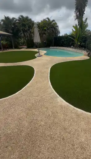 Jardín residencial con caminos curvos y grama artificial
