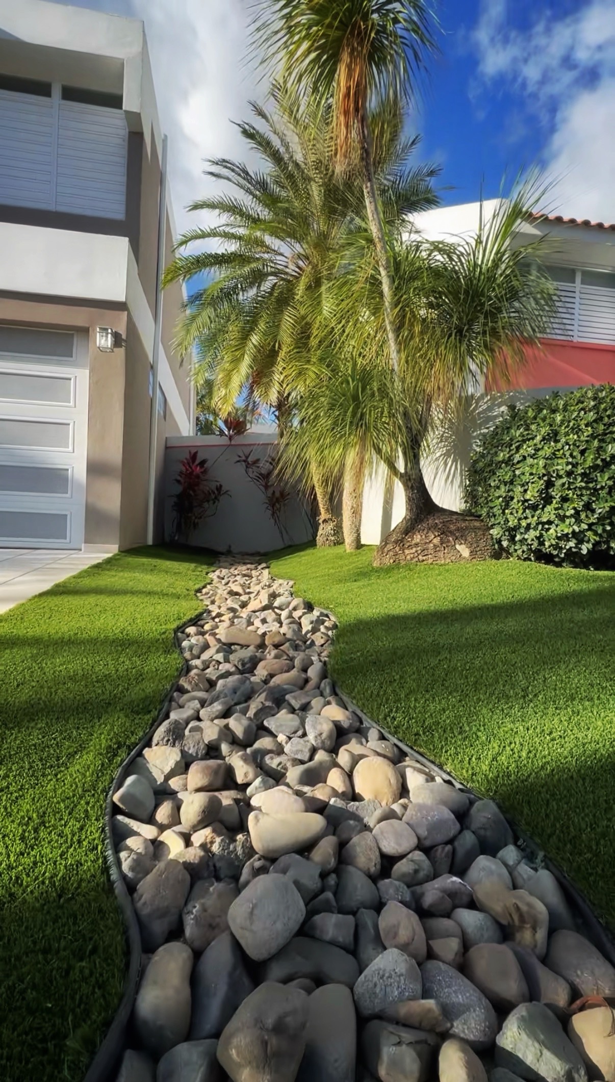 Patio residencial con grama artificial y palmeras